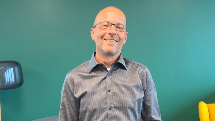 Andreas im AKQUINET Büro vor einer grünen Wand nach seinem Interview, in dem er mehr über seinen Job als IT Service Manager erzählt.